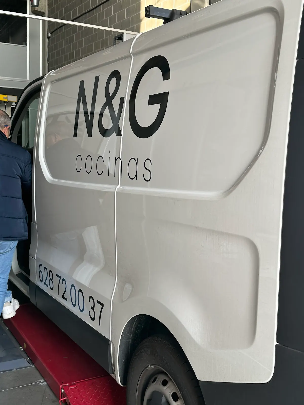 Furgoneta blanca rotulada con el nombre N&G Cocinas, en un espacio interior.