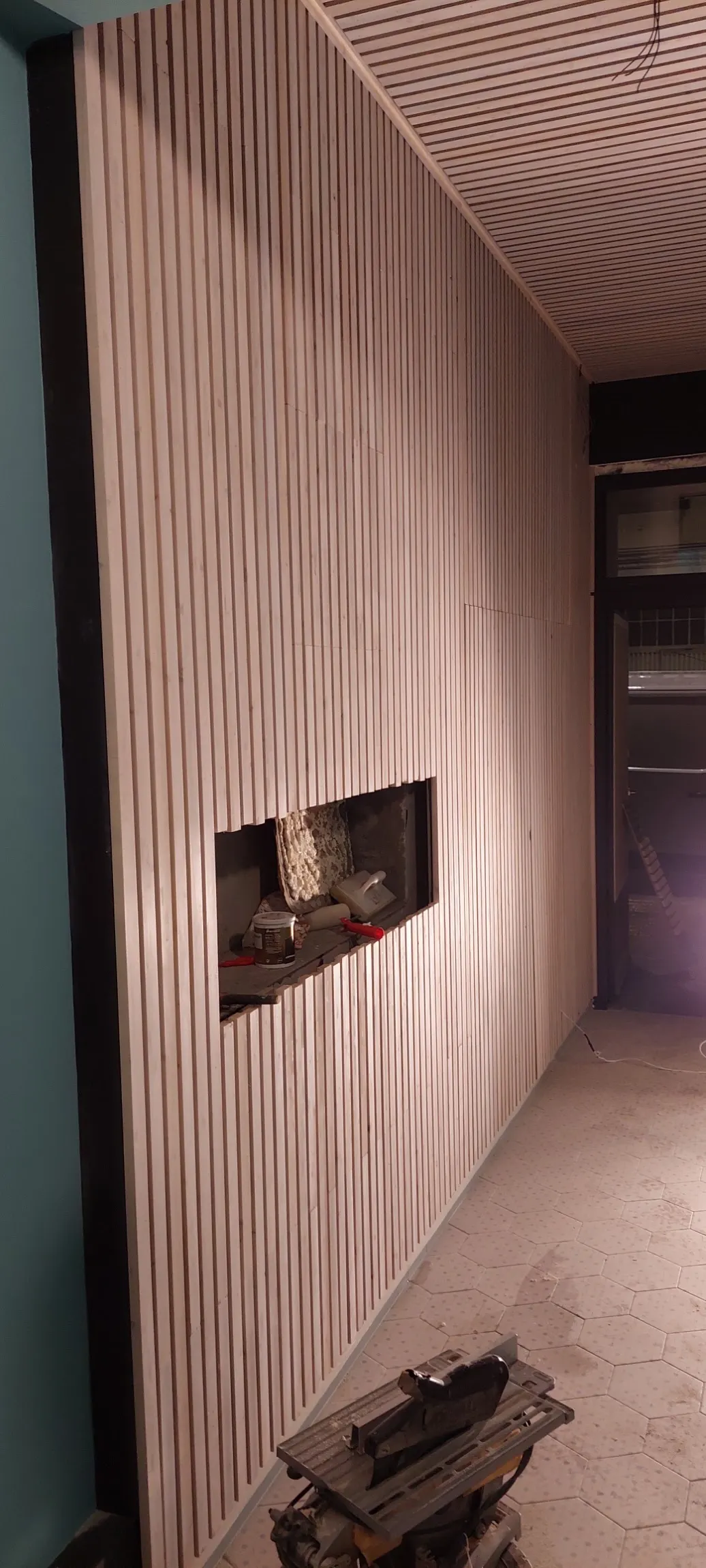 Revestimiento de pared con listones de madera y hueco para chimenea.