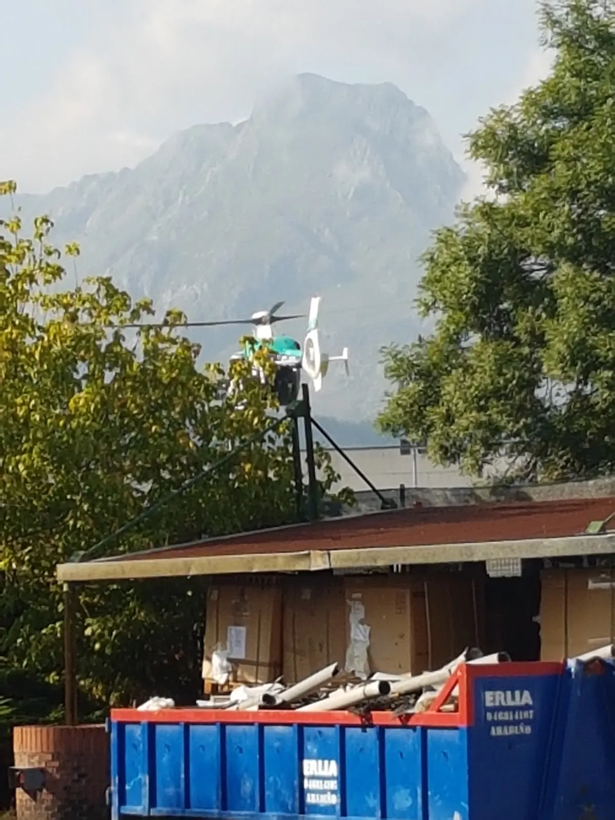 Contenedores de obra junto a una instalación de Rua Proyectos Y Servicios Sl, con montañas al fondo.