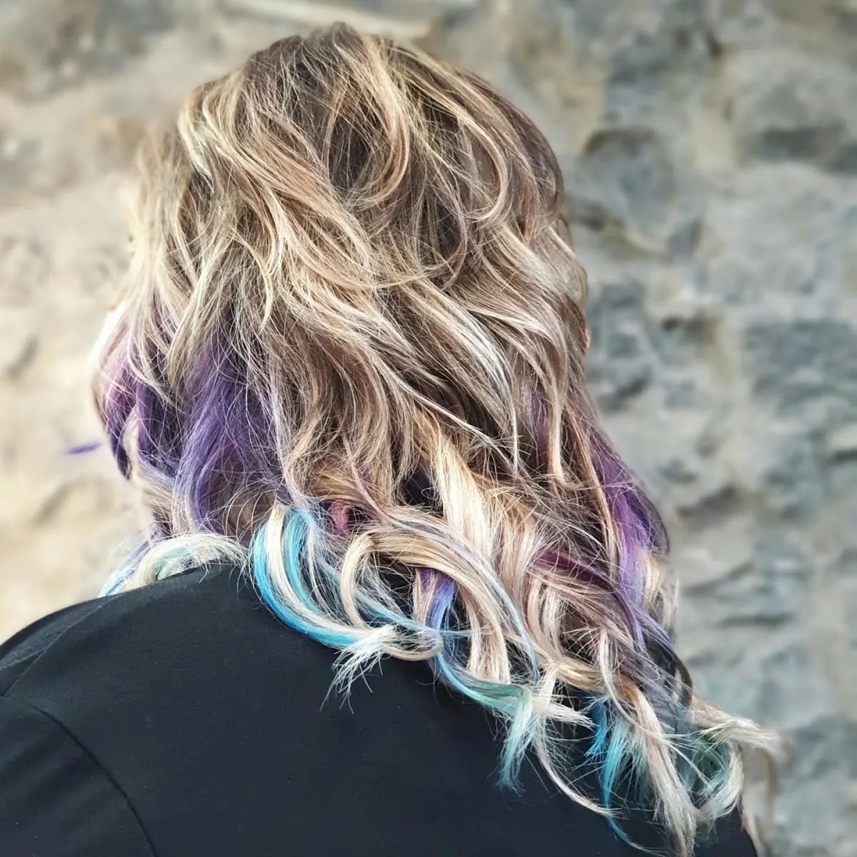 Detalle de un peinado ondulado con mechas de varios colores.
