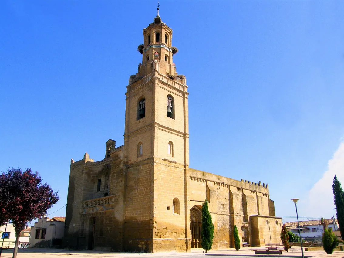 Iglesia de piedra con torre campanario bajo un cielo despejado.