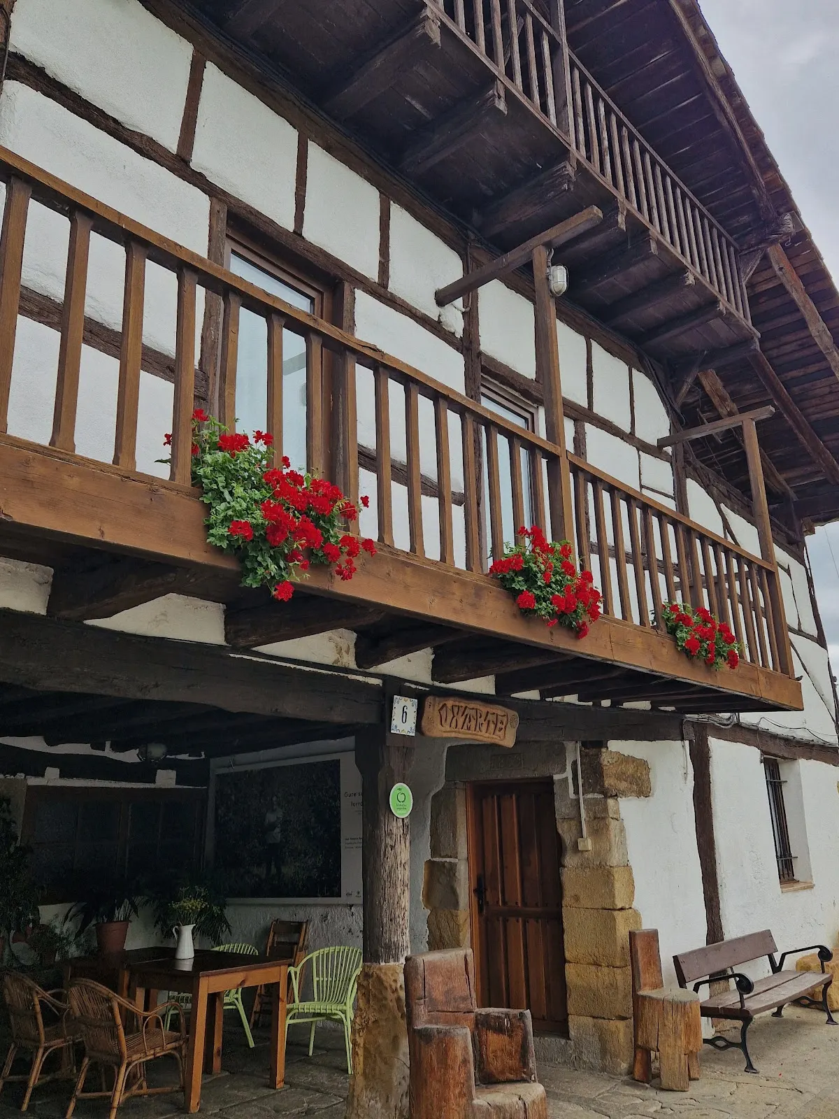 Fachada de caserío tradicional de Sidrería Uxarte, con balcones de madera y flores.