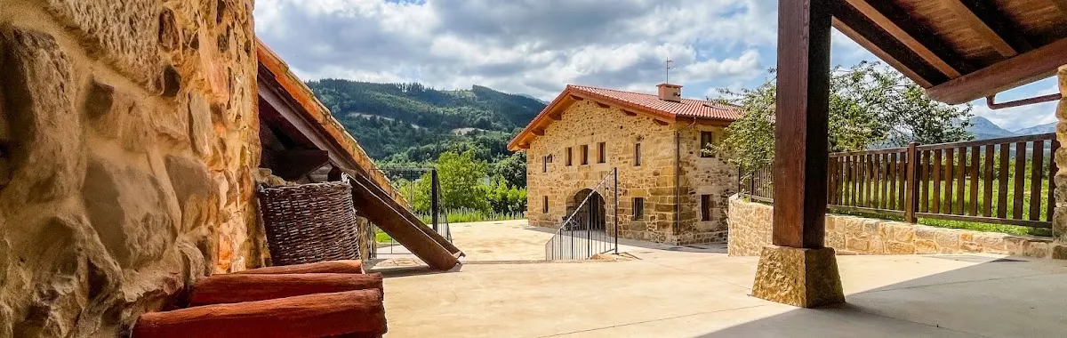 Terraza y edificios de piedra de Solatsu Baserria, con vistas al paisaje verde de Elorrio.