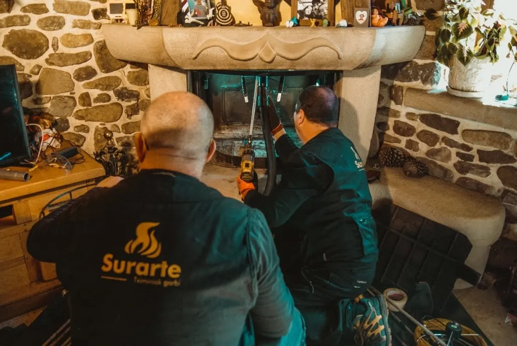 Trabajadores de Surarte realizando una limpieza en una chimenea de piedra.