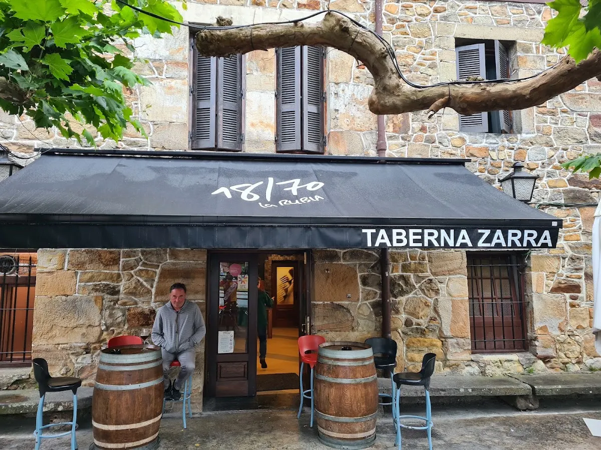 Fachada de Taberna Zarra con terraza y toldo en un edificio de piedra
