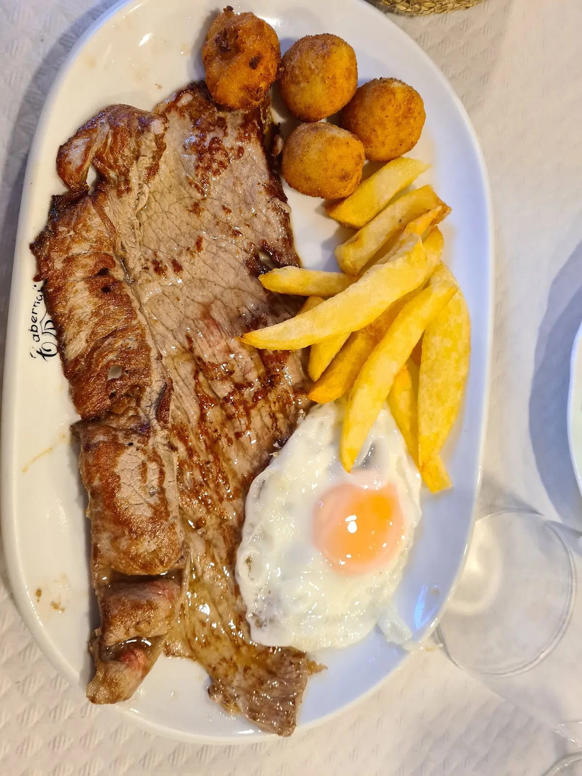 Plato de carne con patatas, huevo y acompañamientos en Taberna Zarra