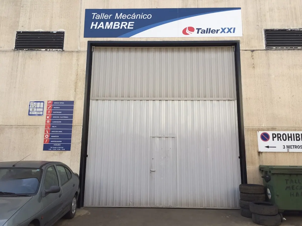 Fachada del taller mecánico Hambre en Mallabia, con la entrada del taller y un coche aparcado delante.