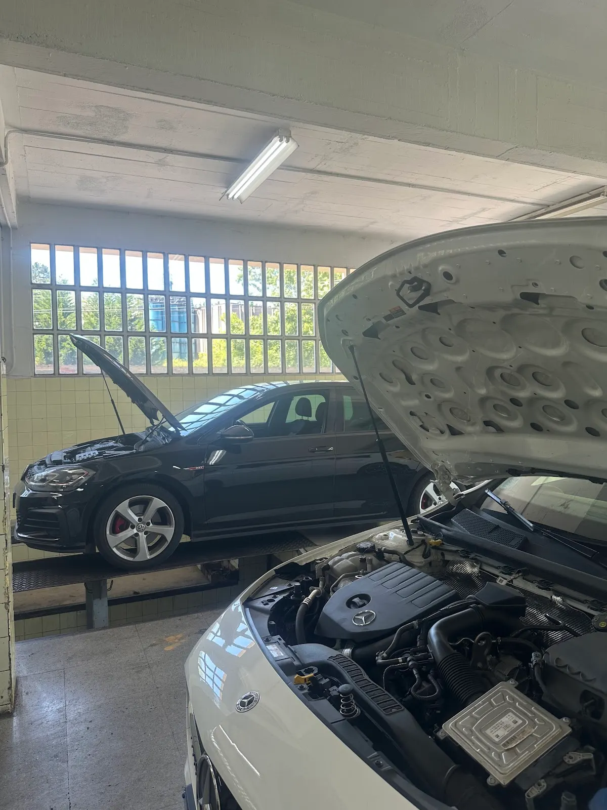 Interior de Talleres San Blas con coches en reparación y capós abiertos
