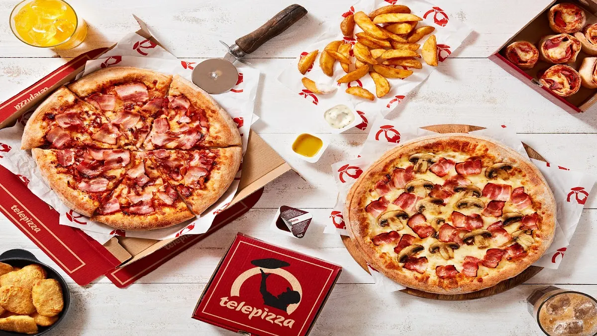 Varias pizzas y acompañamientos de Telepizza servidos sobre una mesa.