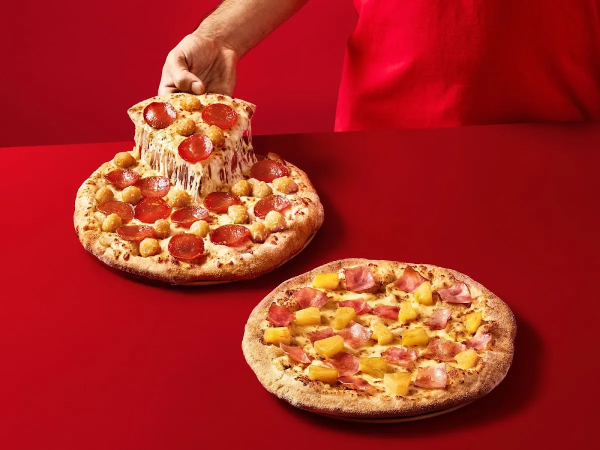 Pizzas de Telepizza, una de ellas levantada para mostrar el queso fundido.