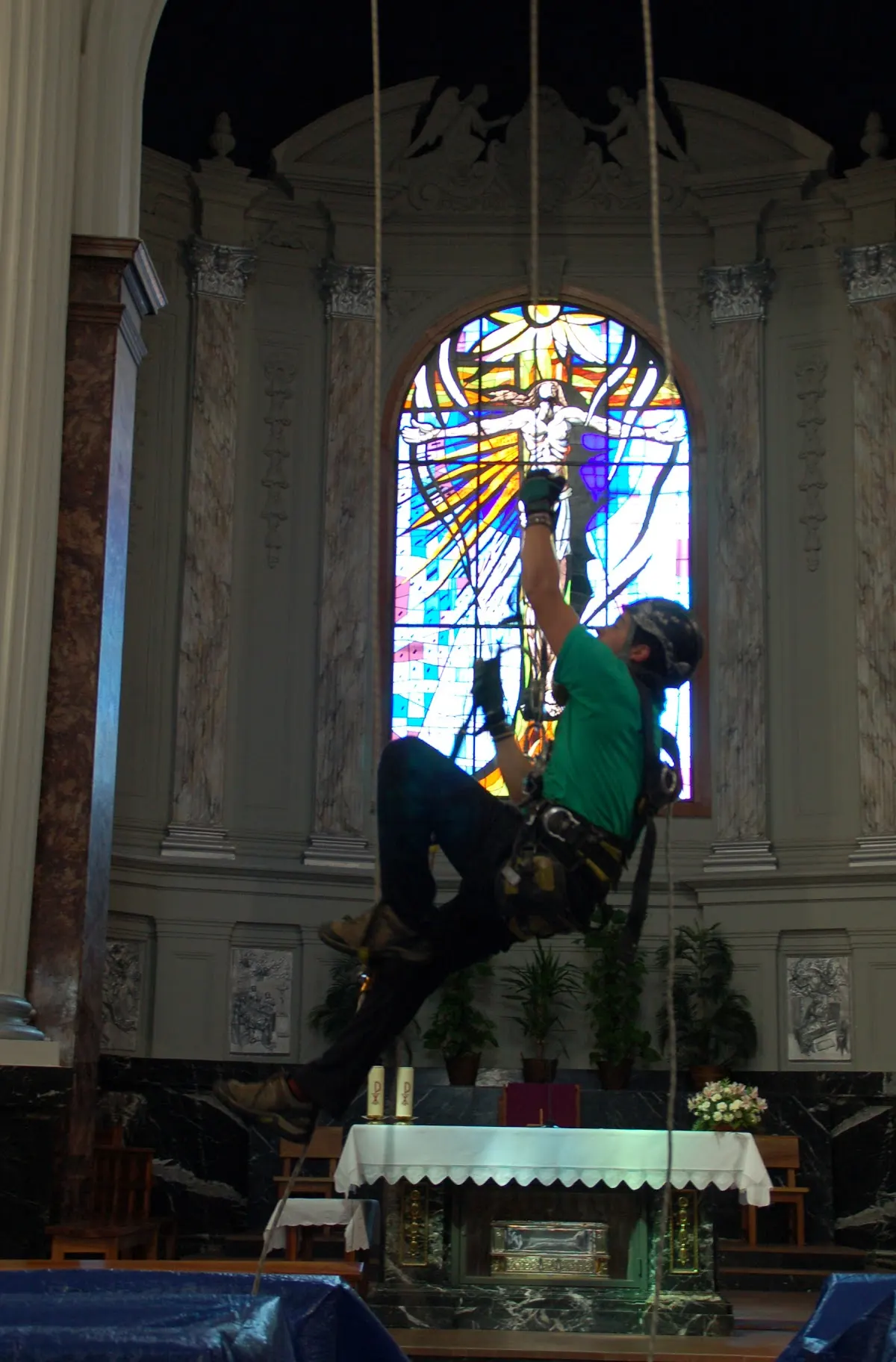 Trabajador suspendido frente a una vidriera en el interior de una iglesia.