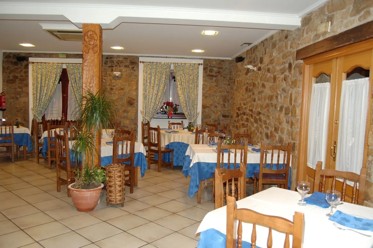 Comedor de Txakoli Larrinagatxu Asador, con paredes de piedra y mesas preparadas.