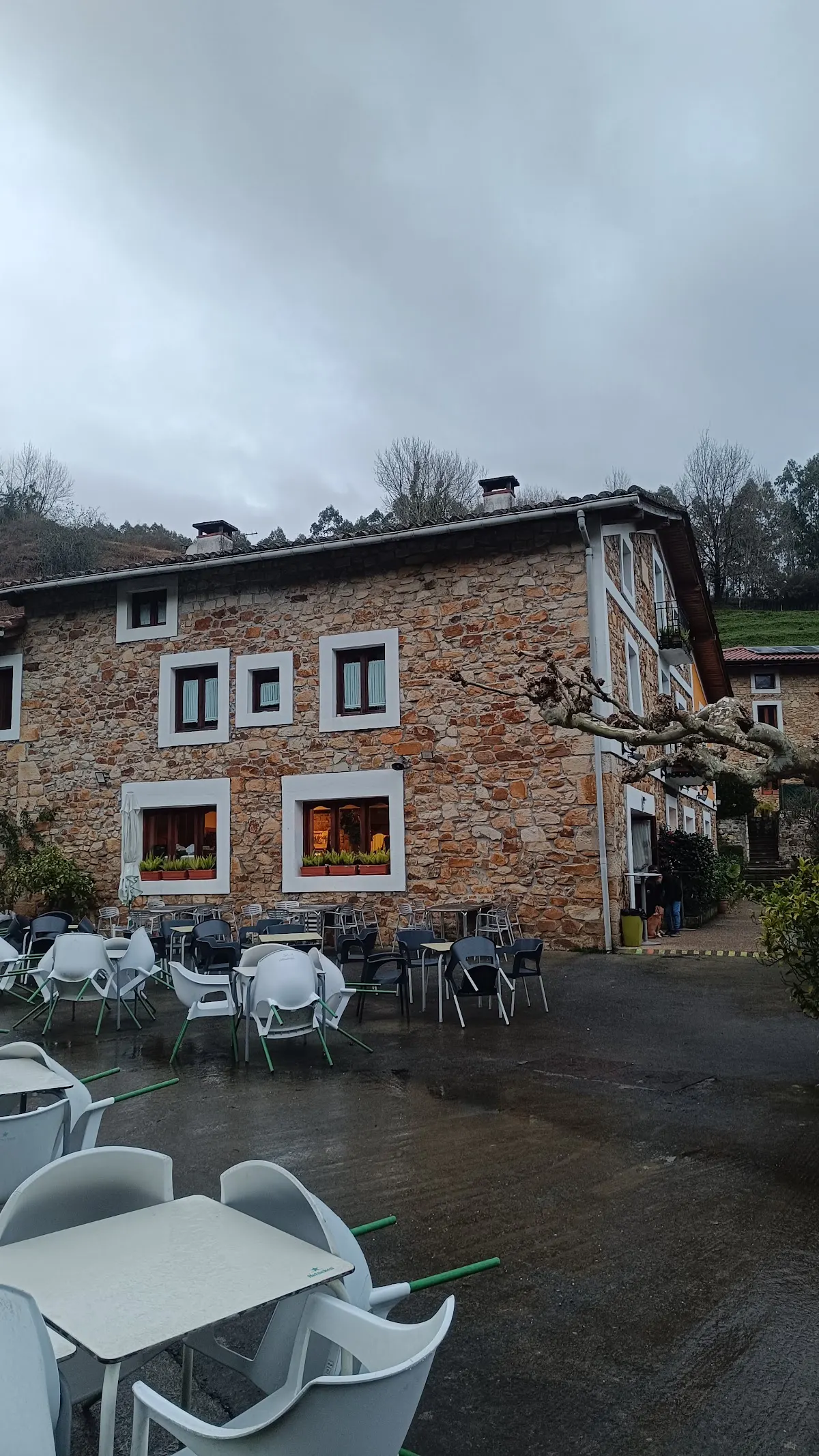 Exterior de piedra de Txakoli Larrinagatxu Asador, con mesas en la terraza.