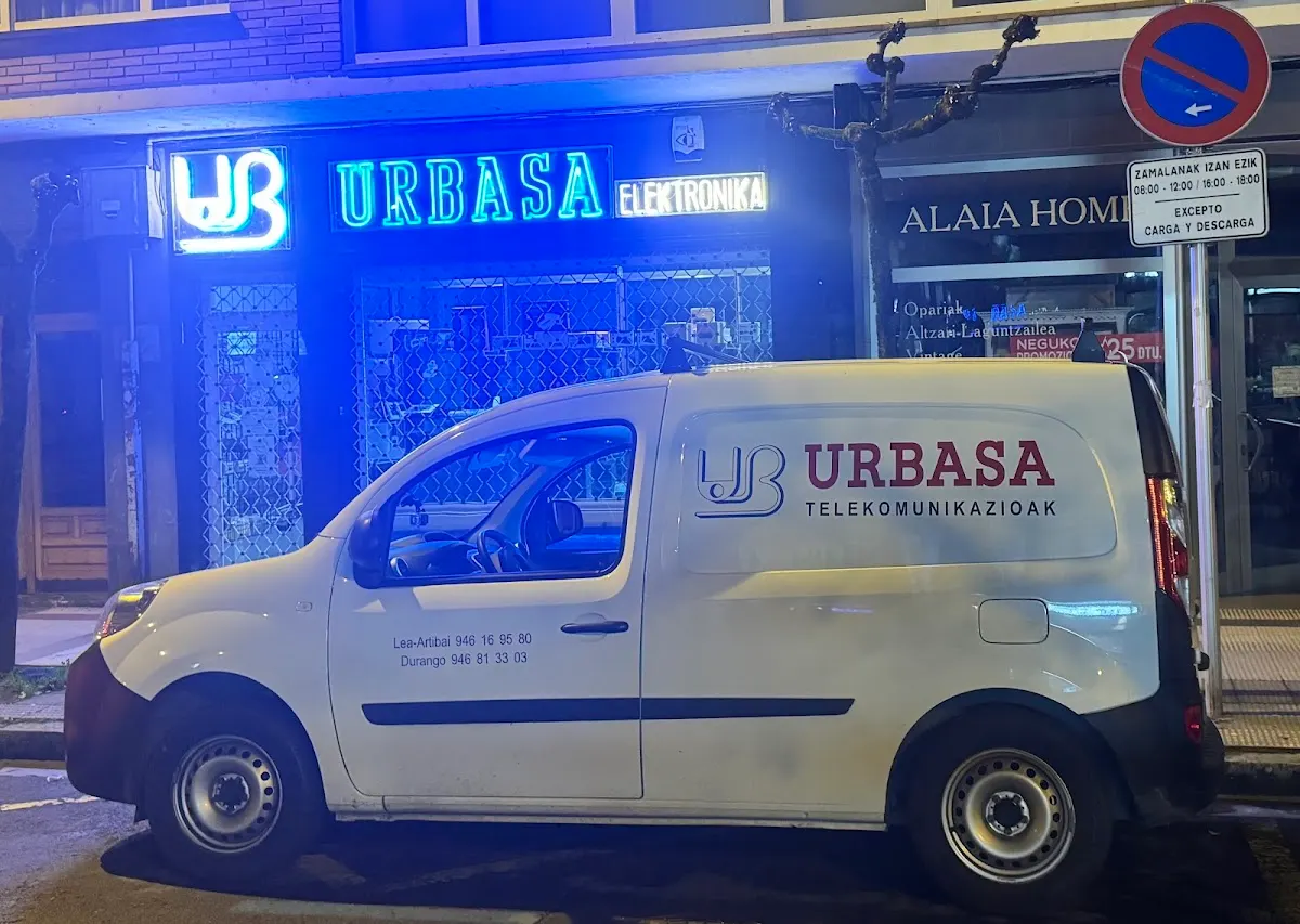 Rótulo iluminado de Urbasa Elektronika y furgoneta de la empresa frente al local.