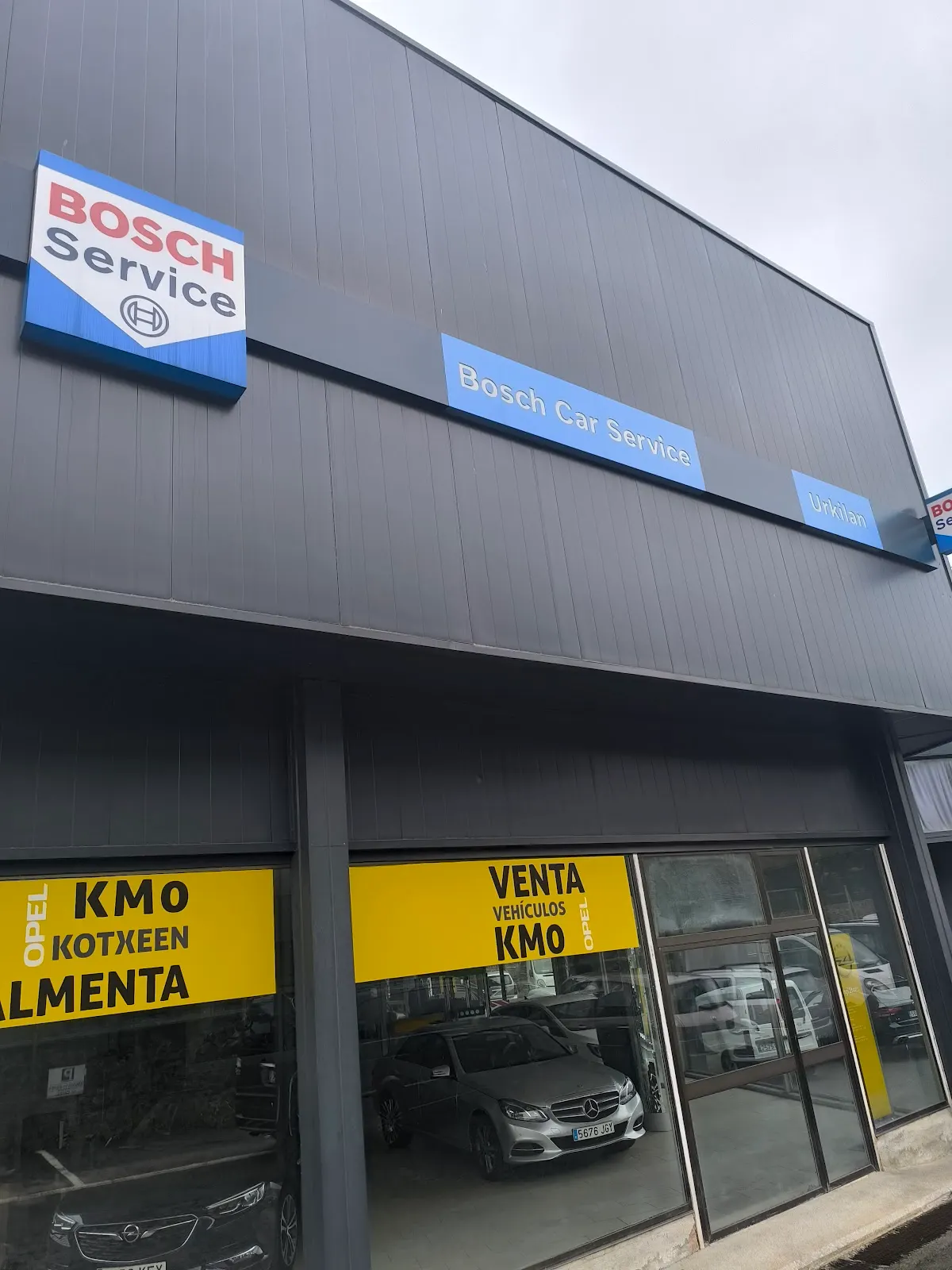 Fachada de Urkilan SL, con rótulos de Bosch Car Service y vehículos en el interior
