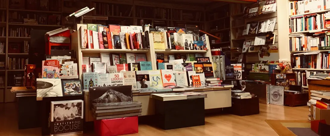 Interior de Urrike Liburudenda con mesas de libros y estanterías hasta el techo.