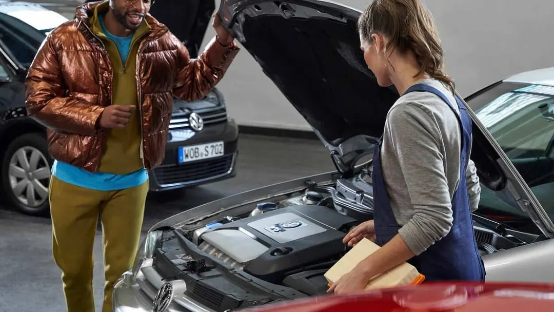 Atención a una clienta junto al motor de un coche en un taller Volkswagen