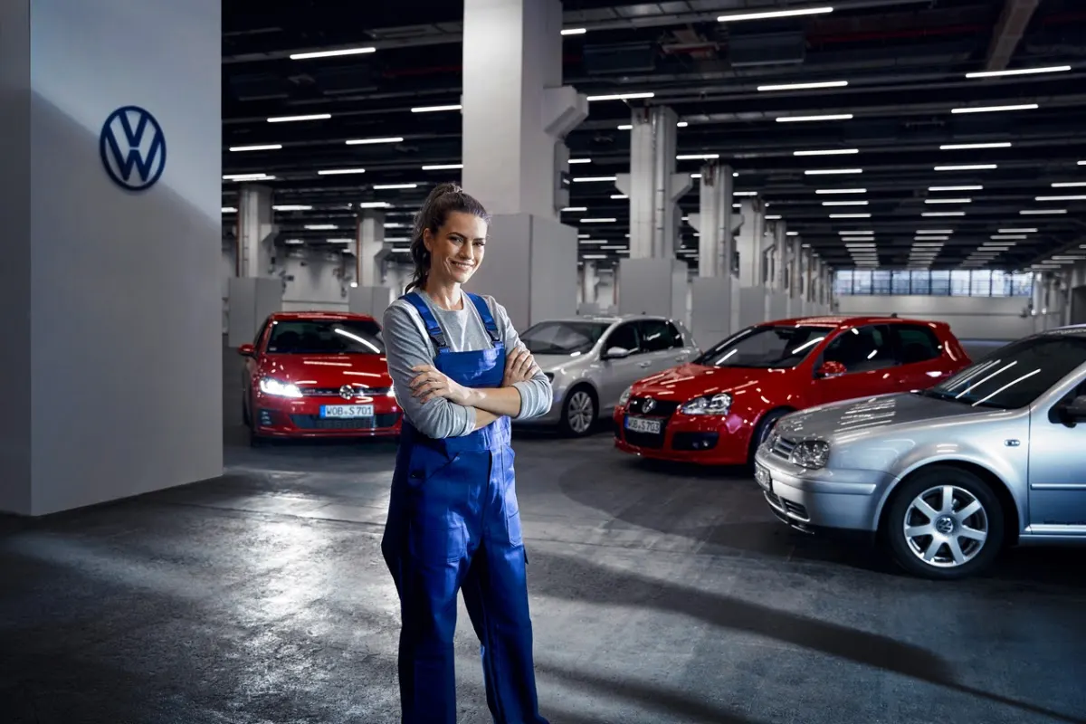Técnica de taller junto a varios coches Volkswagen en el concesionario