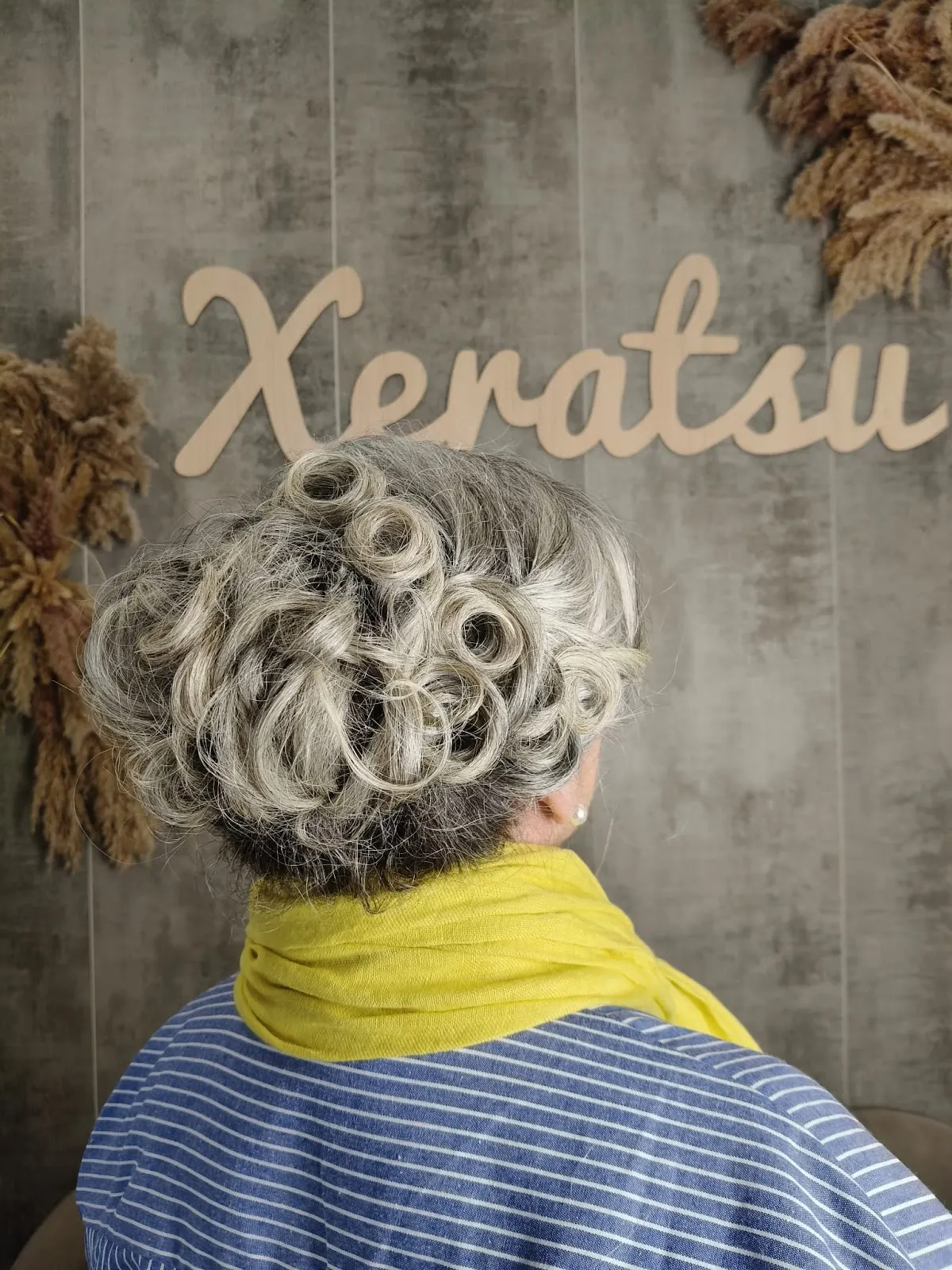 Peinado rizado en XERATSU, con el nombre del salón en la pared.